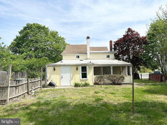 back of property with fence, a chimney, and a yard