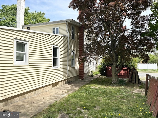 view of home's exterior with a lawn, fence, and a chimney