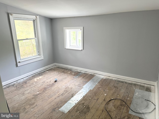 spare room featuring baseboards, vaulted ceiling, and hardwood / wood-style floors
