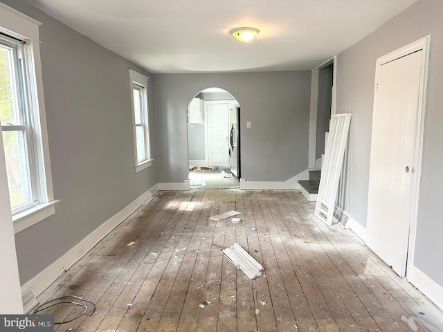 interior space with stairway, arched walkways, baseboards, and hardwood / wood-style flooring
