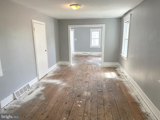 hall with visible vents, baseboards, and hardwood / wood-style floors