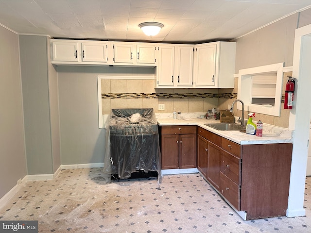 kitchen featuring a sink, light countertops, white cabinetry, baseboards, and light floors
