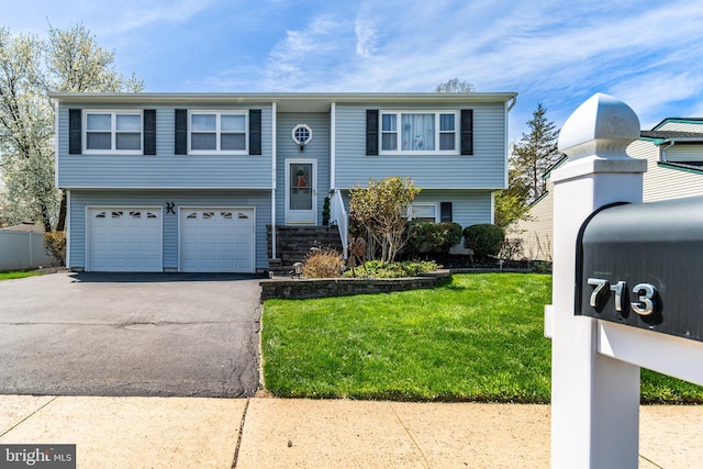 raised ranch with a garage, aphalt driveway, and a front lawn