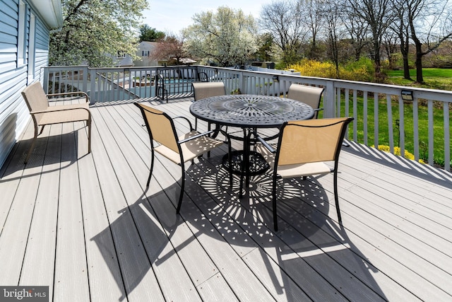 wooden deck featuring a lawn and outdoor dining space