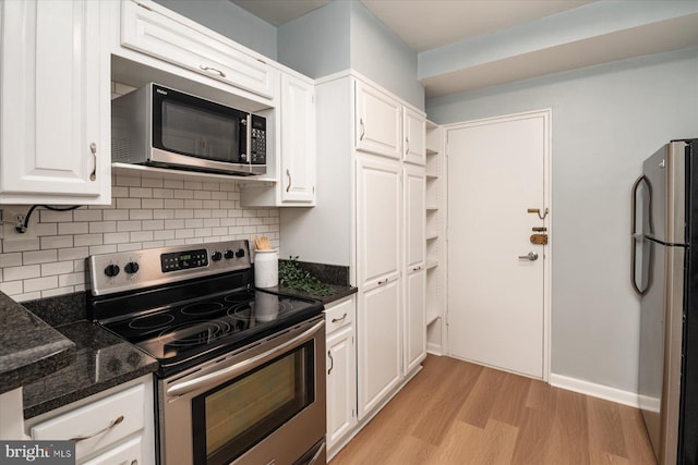 kitchen featuring dark stone counters, white cabinetry, tasteful backsplash, light wood-style flooring, and appliances with stainless steel finishes