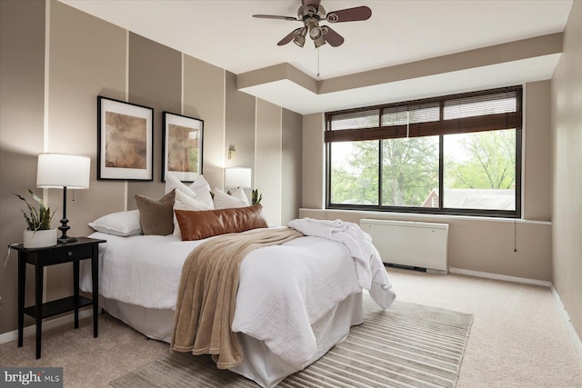 bedroom featuring radiator heating unit, baseboards, ceiling fan, and light carpet