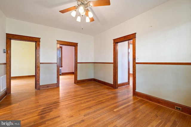 empty room with visible vents, light wood-style flooring, ceiling fan, and baseboards