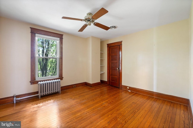 unfurnished room with baseboards, radiator, and hardwood / wood-style floors