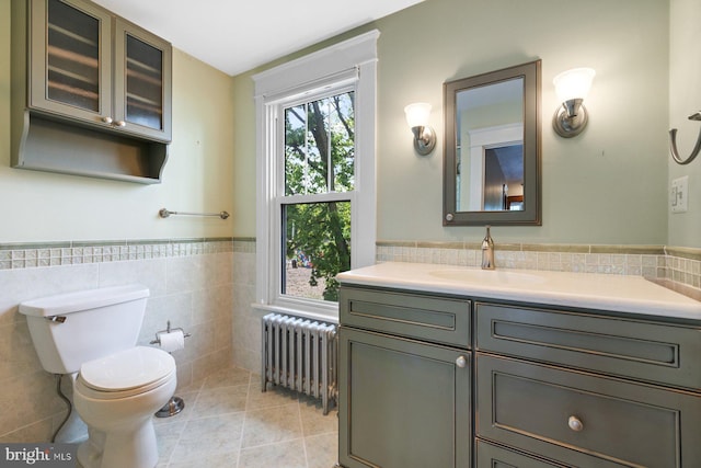 bathroom with vanity, tile patterned floors, radiator, a wainscoted wall, and tile walls