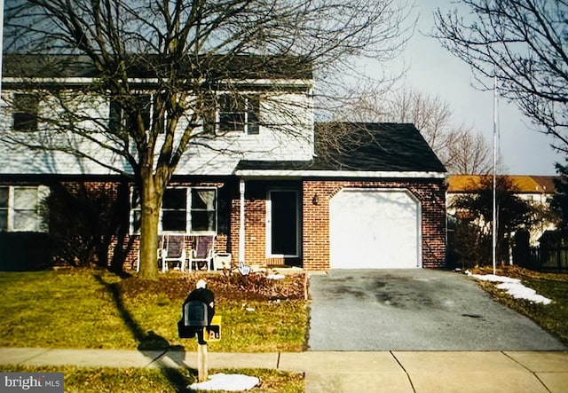 traditional-style house featuring brick siding, a front lawn, driveway, and an attached garage