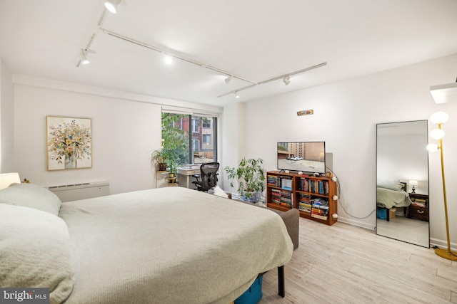 bedroom featuring track lighting, light wood-style floors, and baseboards