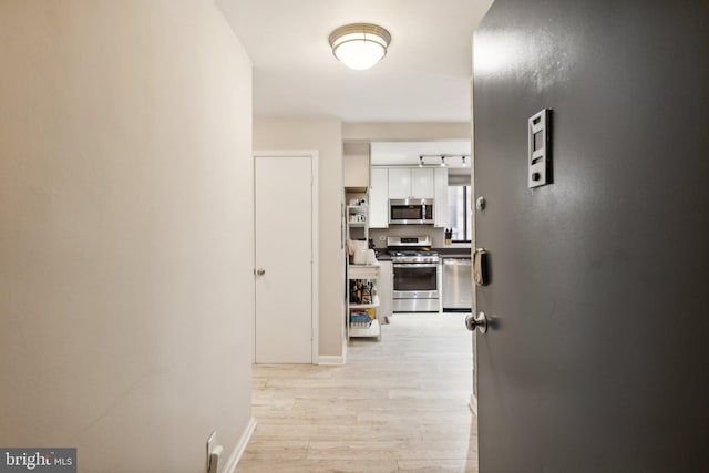 corridor featuring light wood-style floors and baseboards