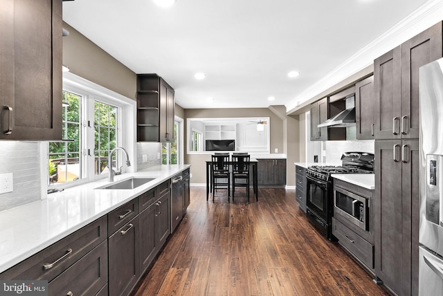 kitchen featuring a sink, appliances with stainless steel finishes, wall chimney exhaust hood, dark wood-style flooring, and dark brown cabinets
