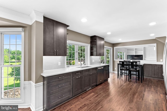 kitchen with a sink, stainless steel dishwasher, dark brown cabinets, dark wood-style flooring, and light countertops