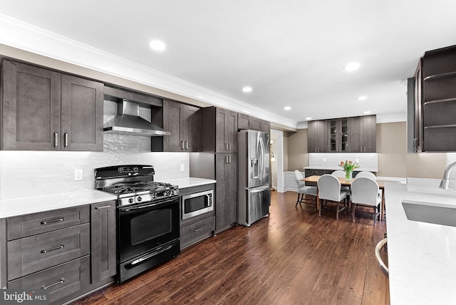 kitchen featuring stainless steel appliances, wall chimney exhaust hood, crown molding, a sink, and light countertops