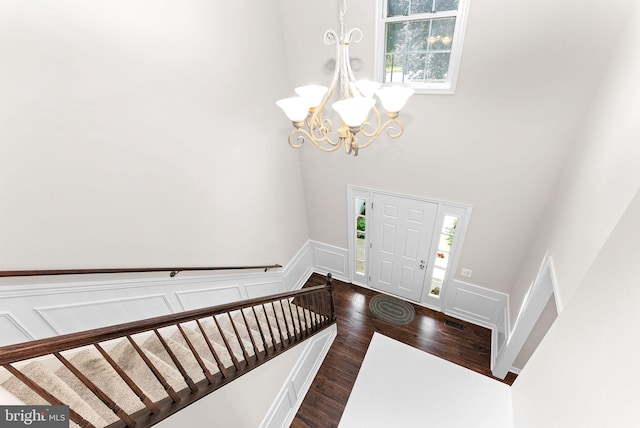 entrance foyer featuring a chandelier, a decorative wall, healthy amount of natural light, a wainscoted wall, and dark wood-type flooring