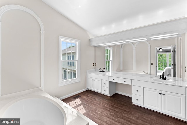 bathroom with lofted ceiling, double vanity, wood finished floors, a bathtub, and ensuite bathroom