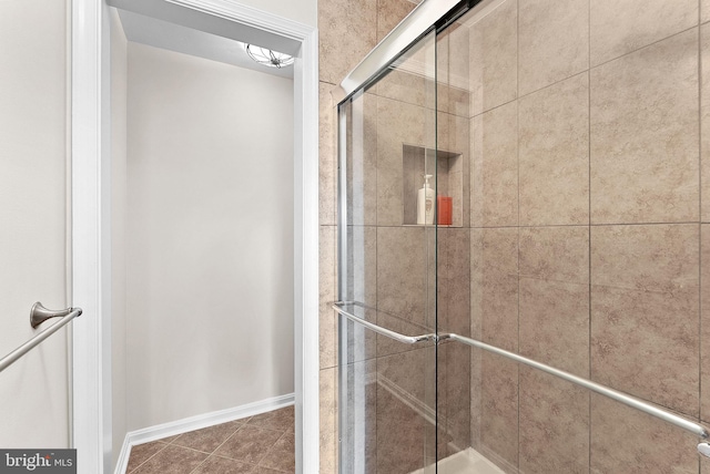 bathroom with a stall shower, tile patterned flooring, and baseboards