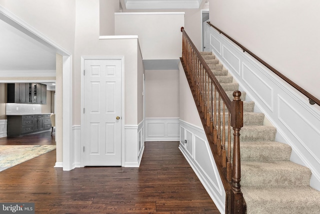 stairway with wood finished floors, wainscoting, and a high ceiling