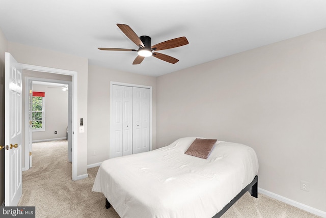 bedroom featuring light colored carpet, baseboards, and a closet