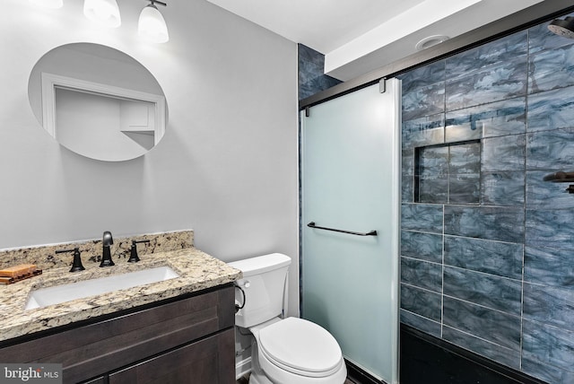 full bathroom featuring a stall shower, toilet, and vanity