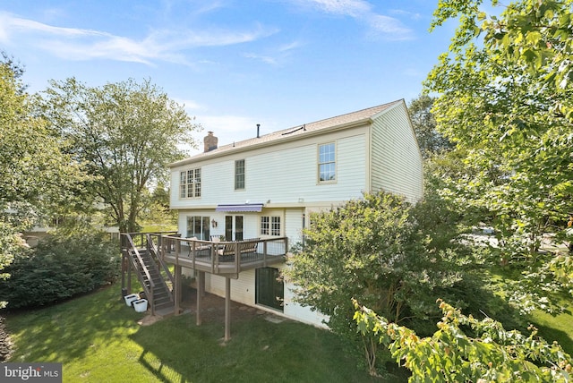 rear view of house featuring stairs, a wooden deck, a chimney, and a lawn