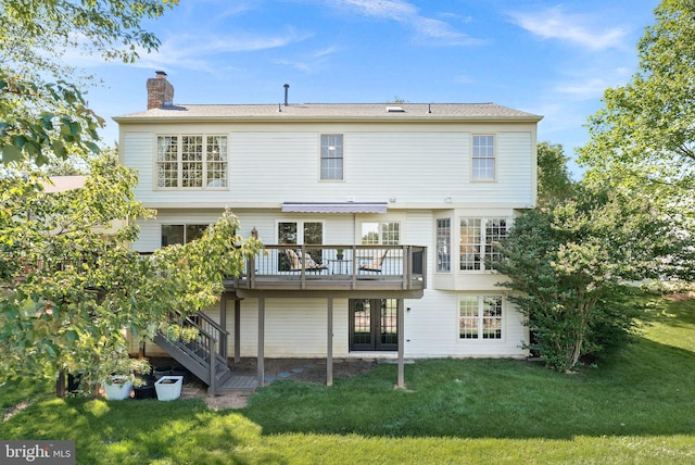 rear view of house with a chimney, a deck, and a yard