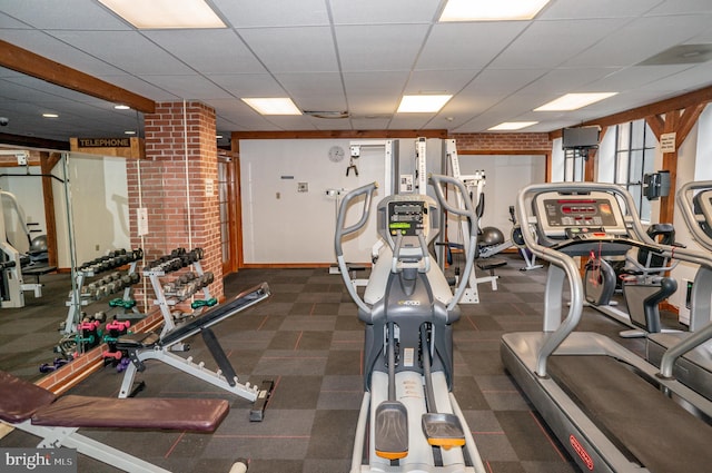 exercise room with a paneled ceiling and carpet