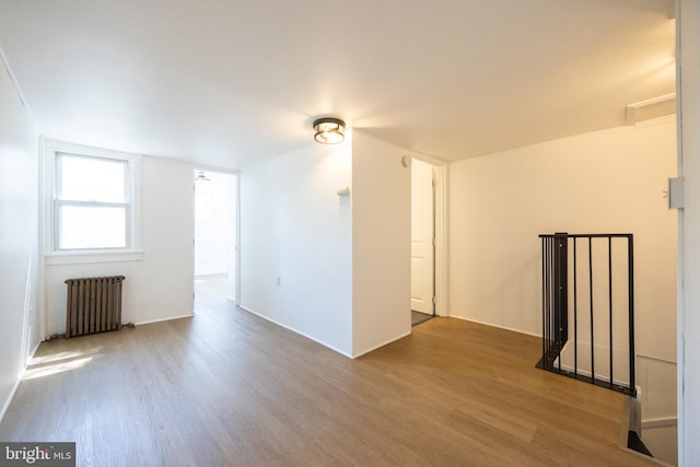 spare room featuring wood finished floors and radiator