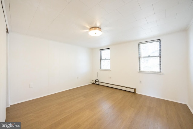 unfurnished room with baseboards, wood finished floors, and a baseboard radiator