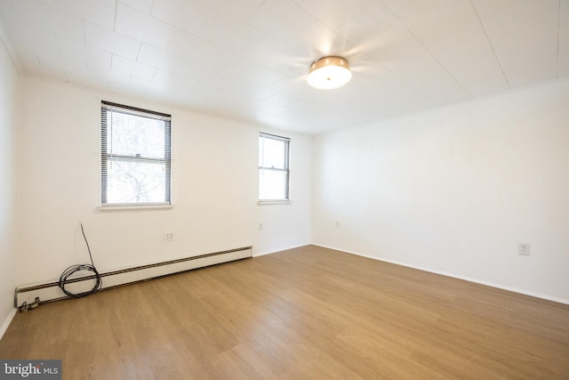 empty room with wood finished floors and baseboard heating