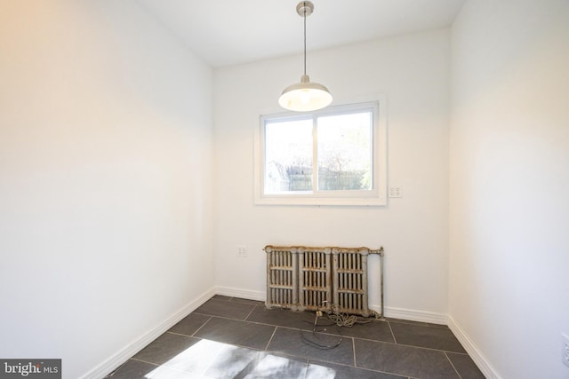spare room with radiator heating unit, dark tile patterned flooring, and baseboards