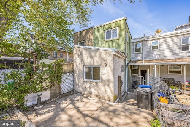 rear view of property with fence, a patio area, and stucco siding