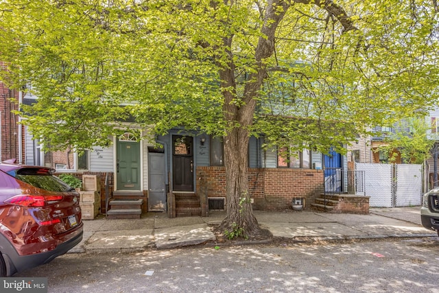 view of property hidden behind natural elements with brick siding and entry steps