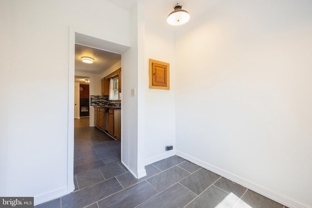 corridor featuring dark tile patterned floors and baseboards