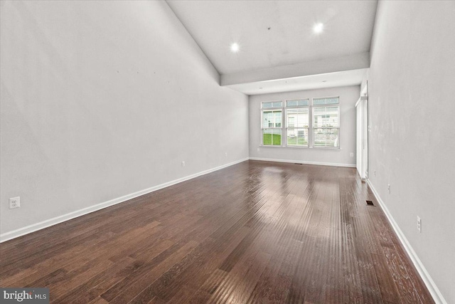empty room with baseboards and dark wood-type flooring
