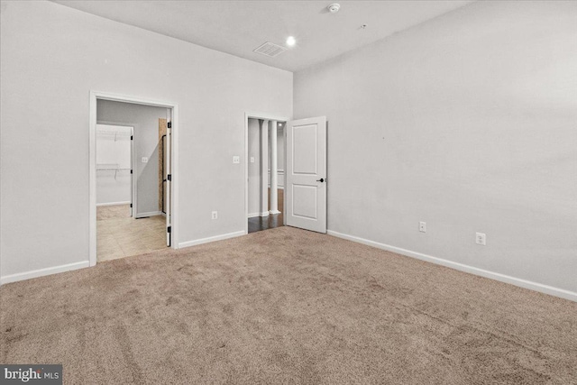 unfurnished bedroom with baseboards, carpet flooring, and a spacious closet