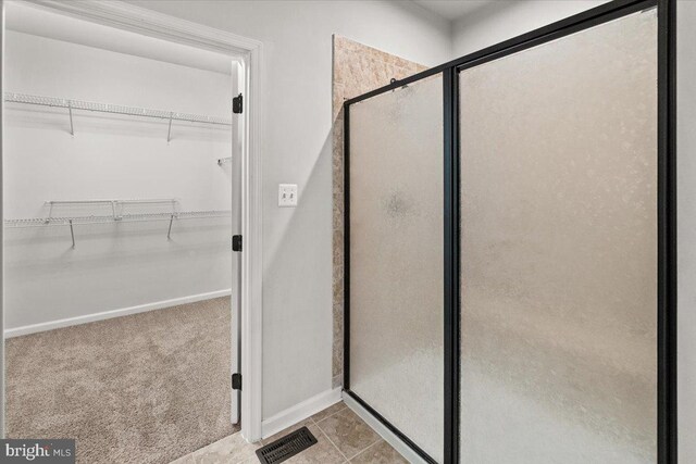 full bathroom featuring baseboards, visible vents, a spacious closet, and a stall shower