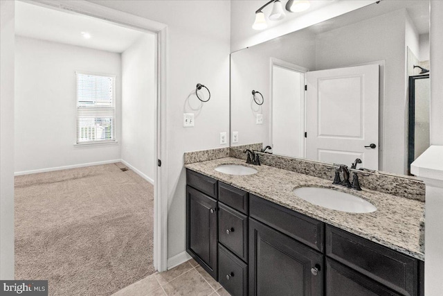 full bath with double vanity, baseboards, and a sink