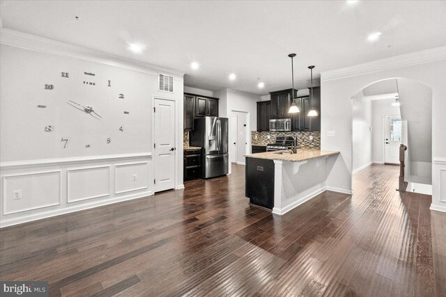 kitchen with crown molding, appliances with stainless steel finishes, a sink, arched walkways, and visible vents