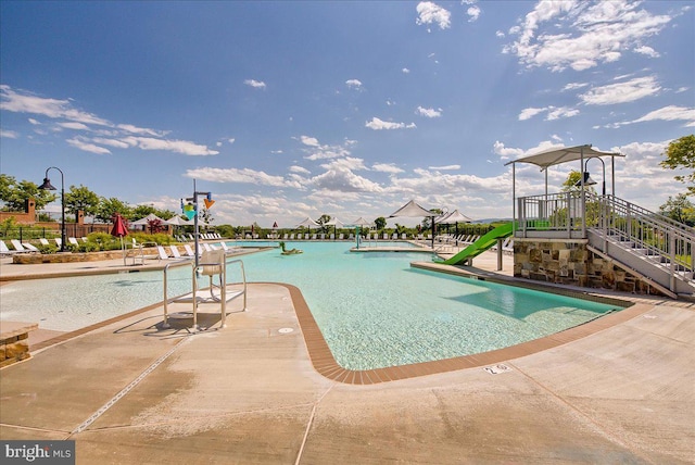 pool with a patio, a water play area, and a water slide