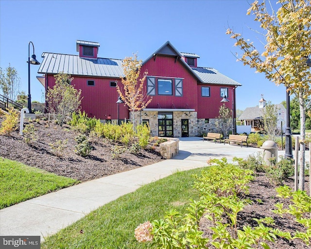 view of front of house with a patio area, fence, a standing seam roof, and metal roof