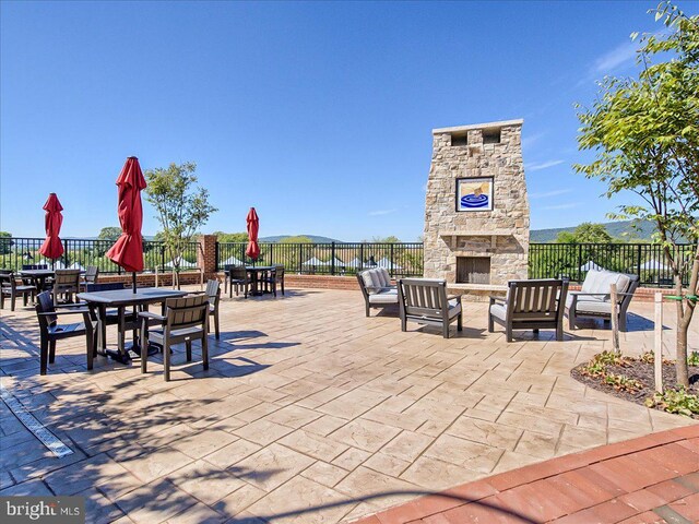 view of patio / terrace with an outdoor stone fireplace, fence, and outdoor dining space
