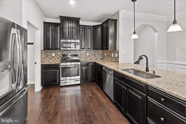 kitchen featuring dark cabinets, a sink, light stone countertops, and stainless steel appliances