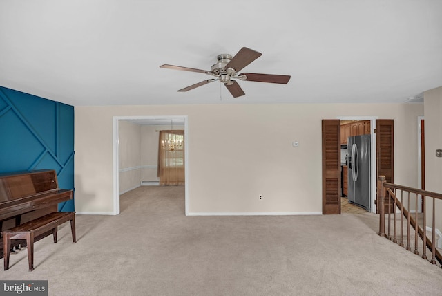 interior space featuring baseboard heating, baseboards, light colored carpet, and ceiling fan with notable chandelier