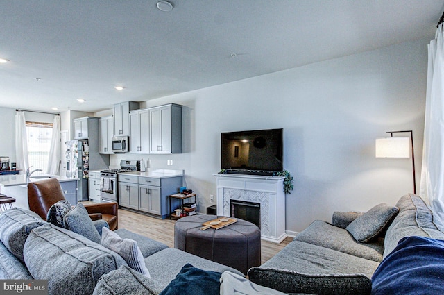 living room featuring a tiled fireplace, recessed lighting, and light wood finished floors
