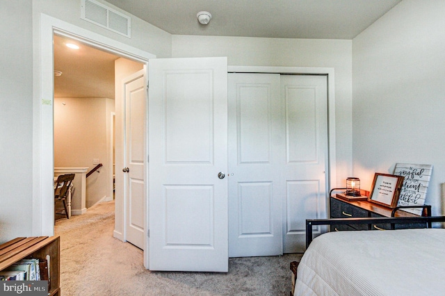 bedroom with a closet, visible vents, and light carpet