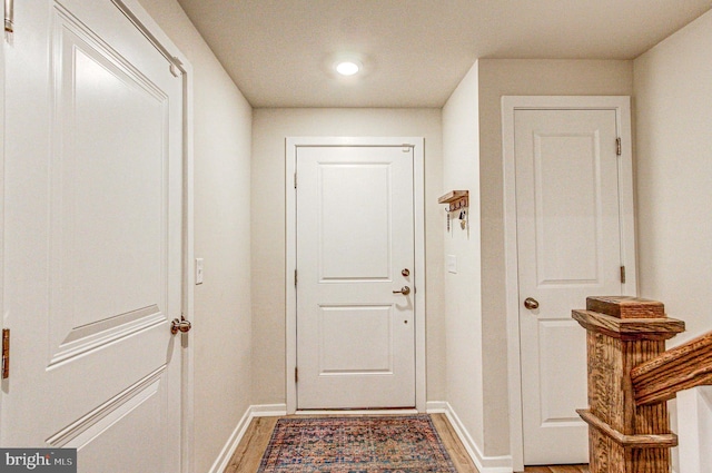 doorway featuring light wood finished floors and baseboards