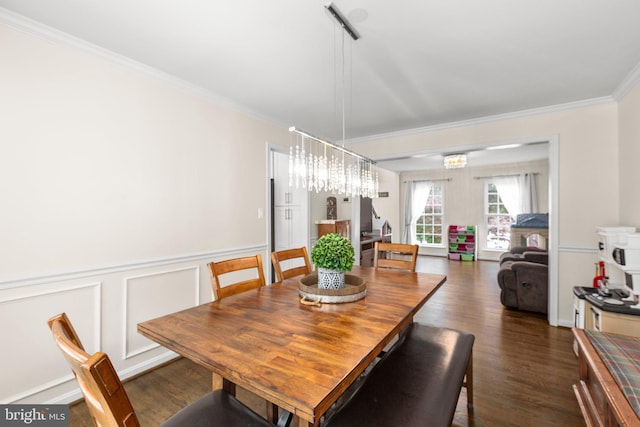 dining space with an inviting chandelier, a decorative wall, ornamental molding, a wainscoted wall, and dark wood-style flooring