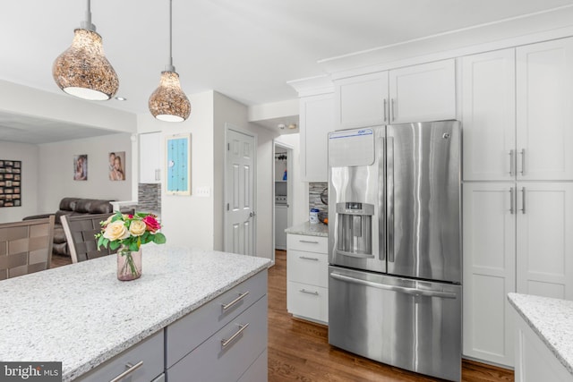 kitchen featuring dark wood-style flooring, stainless steel fridge, light stone counters, white cabinetry, and open floor plan
